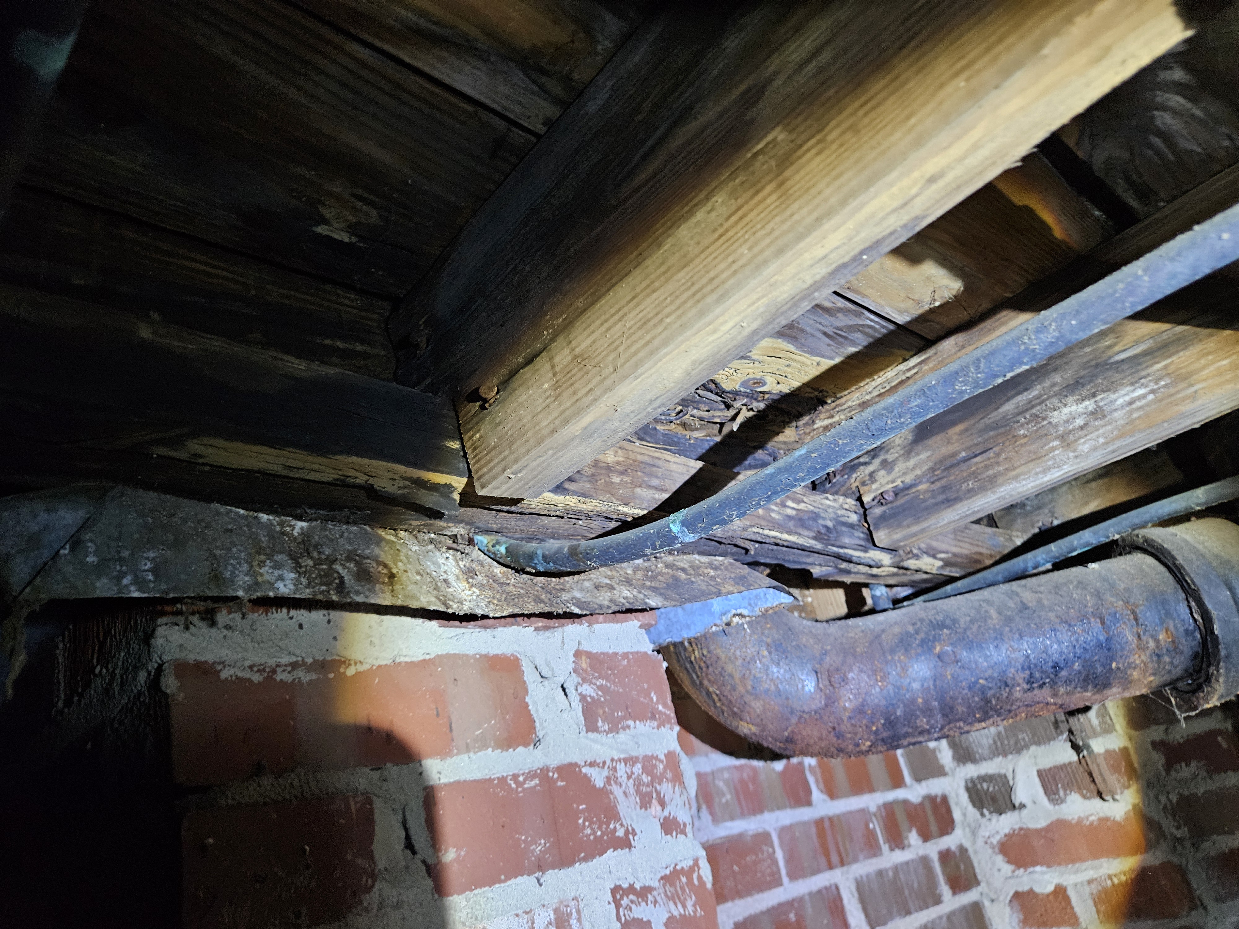 Deteriorated floor joists and subfloor in a crawl space — long-term moisture damage to the home's support structure.